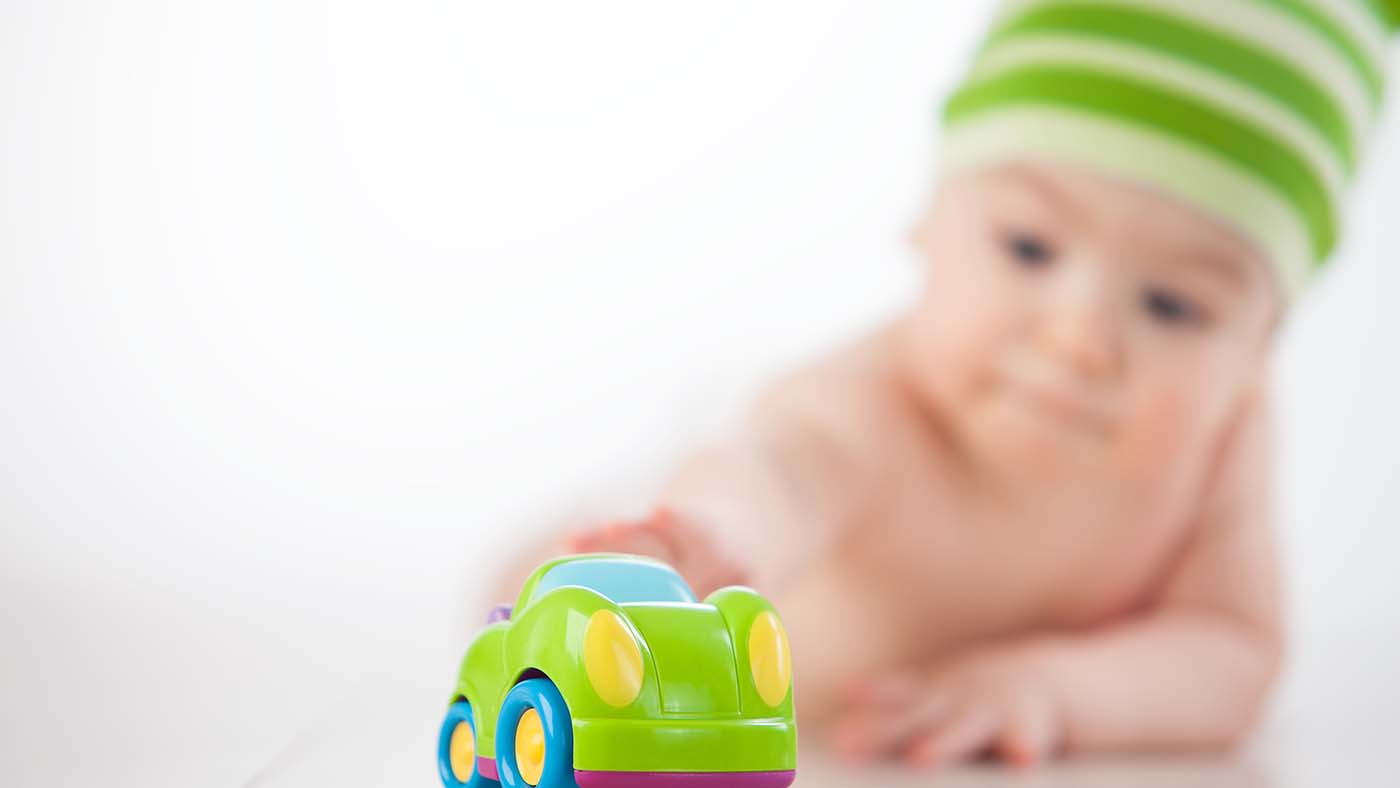 Can you come and get it? Encourage your baby to change position using small, wheeled toys - Featured Image